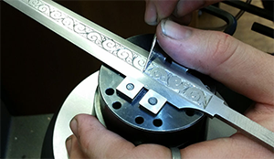 Ein gestaltetes Werkstück aus Metall mit einem Relief-Ornament wird bearbeitet