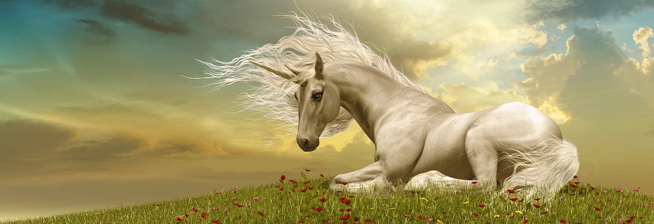 Auf einer grünen Wiese liegt ein Einhorn. Durch die Wolken am Himmel bricht die Sonne durch.