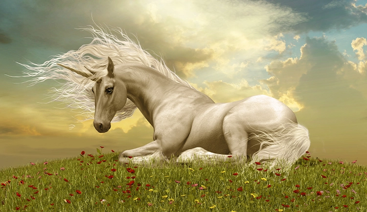 Auf einer grünen Wiese liegt ein Einhorn. Durch die Wolken am Himmel bricht die Sonne durch.