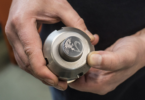 Eine Hand hält die Stempelhalterung mit dem Stempel für die 2-Euro- Münze.