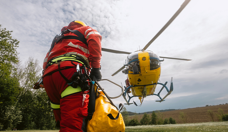 Collage mit dem Foto eines Rettungshubschraubereinsatzes sowie der 10-Euro-Polymerringmünze „Rettungsdienste“